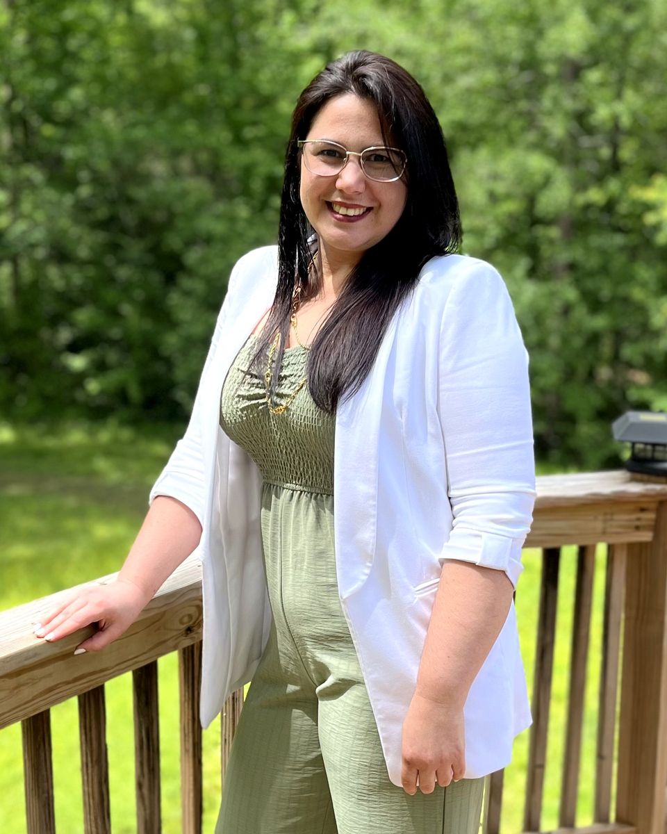 Yainett Carbot Solis, fundadora de Finanzas Seguras, sonriendo en una terraza al aire libre, con chaqueta blanca y lentes.